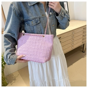 Sac fourre-tout en tweed rose avec chaîne dorée présenté dans un cadre décontracté