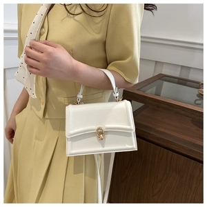 Borsa quadrata in pelle bianca con fibbia dorata portata da modella in blazer giallo