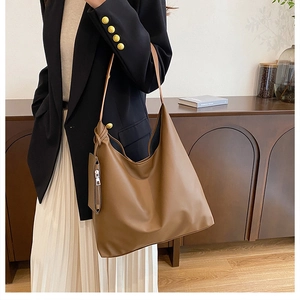 Detail of coffee brown tote bag with detachable pouch worn with a black blazer