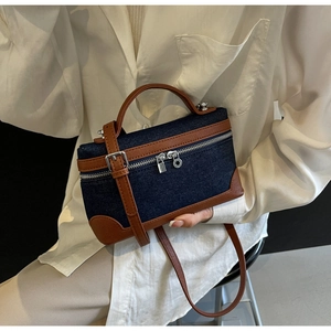 Detail of color-block denim crossbody bag with brown leather trim and silver zippers
