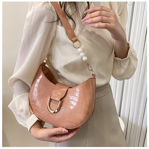 Detailed shot of pink crocodile texture shoulder bag with pearls and golden metal buckle