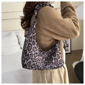 Detail of leopard print tote bag with ruffled shoulder strap worn over a brown sweater