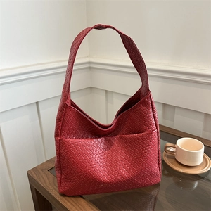 Large red woven hobo tote bag with classic intrecciato design on a wooden desk
