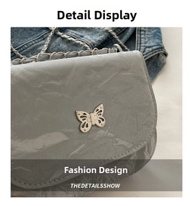 Close-up of grey pleated patent leather crossbody bag with silver butterfly twist lock