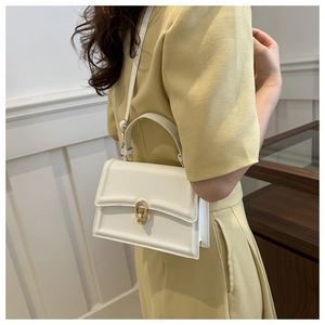 Dettaglio di una borsa bianca quadrata con fibbia dorata su un abito giallo chiaro