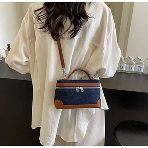 Detail of denim and leather crossbody bag with silver zippers and contrast trim