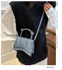 Detail view of denim texture hourglass bag with knot handle and curved base