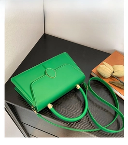 Top view of a vintage green leather crossbody bag with gold buckle on dark wood table