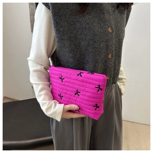 Detail einer leuchtend rosa gesteppten Cord-Clutch mit schwarzen Schmetterlingsstickereien
