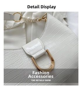 Close-up of white croc-embossed texture with gold D-ring buckle and pearl strap detail