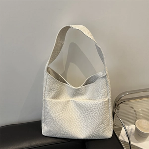 Chic white woven textured hobo tote bag with wide shoulder strap on a black bench