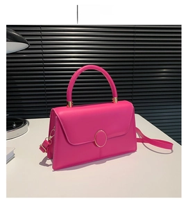 Detail of rose red leather handbag with gold metal clasp and adjustable shoulder strap