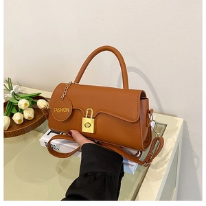 Detail of caramel faux leather bag with golden padlock closure and fashion tag