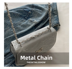 Detail of silver butterfly buckle and marble pattern on grey saddle bag with chain