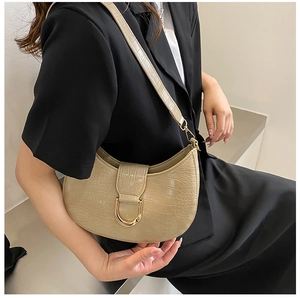 Detail of beige faux crocodile leather hobo bag with a gold D-ring buckle on a model