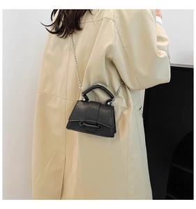 Détail du mini sac bandoulière noir grainé avec chaîne à boules argentée sur manteau