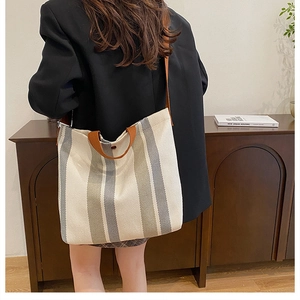 Vertical striped canvas tote bag with brown leather straps shown on a model