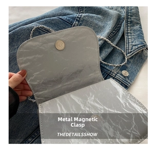 Macro shot of silver pleated saddle bag with metallic magnetic closure detail