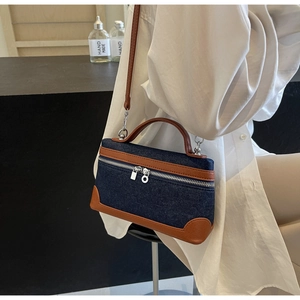 Close-up of the denim patchwork handbag with brown leather trim and silver metal zippers