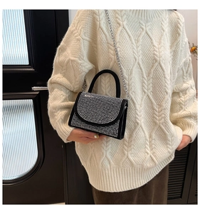 Detail der schwarzen Mini-Handtasche mit silbernen Strasssteinen und Metallkettenriemen