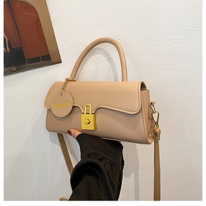 Detail of beige faux leather handbag with gold lock and circular fashion charm tag