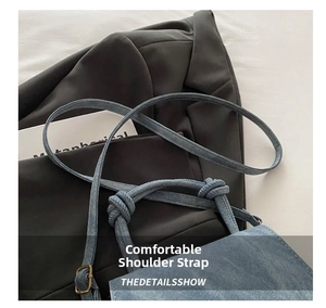 Detail of blue denim shoulder bag featuring a knotted rope strap and bronze metal buckle