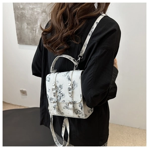 Detail of artistic ink butterfly backpack shown on model highlighting the strap and design