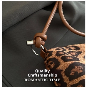 Detail of leopard print bag with brown leather strap knotted on silver metal ring