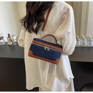 Detail view of denim and leather crossbody bag with adjustable strap and handles