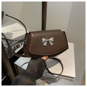 Detail of dark brown vintage crossbody bag featuring a silver metal bow buckle