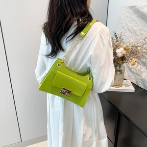 Neon green leather square shoulder bag with gold chain strap worn by a model in white