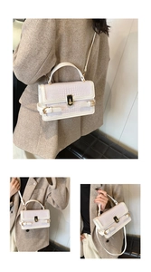 Detail of white crocodile embossed texture on a crossbody bag with gold metal buckle