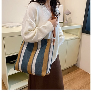 Detailed shot of striped canvas tote bag with wide brown strap and large capacity