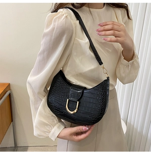 Close-up of black croc-effect leather underarm bag with gold U-shaped metal buckle