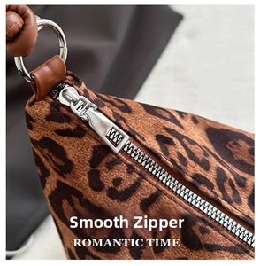 Detailed close-up of the smooth silver zipper and leopard print plush fabric texture