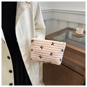 Détail de la pochette en velours côtelé matelassé beige avec broderie papillon noire
