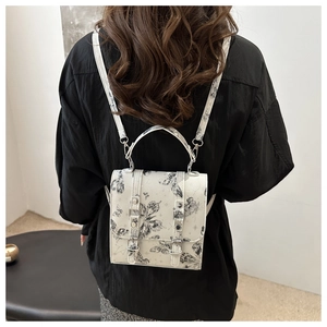 Detail of vintage cream backpack with black butterfly prints and dual buckle straps