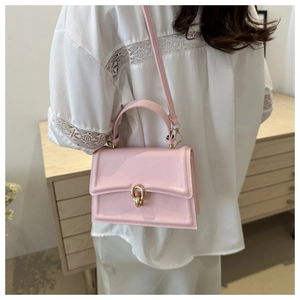 Piccola borsa quadrata rosa con chiusura dorata e tracolla regolabile indossata da modella