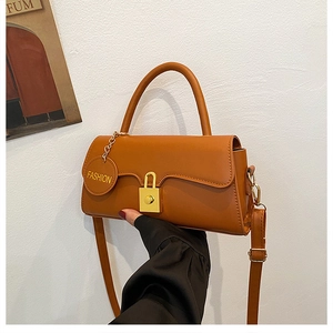 Detail of caramel faux leather bag featuring a gold buckle and adjustable strap