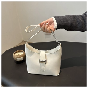 Close-up of a white minimalist shoulder bag with silver metal buckle and chain strap