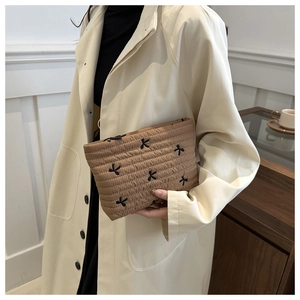 Brown quilted corduroy clutch bag with black butterfly embroidery held by a model