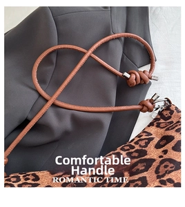 Close-up of leopard print shoulder bag with brown leather knotted handle and silver accents