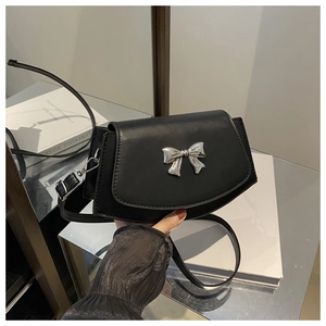 Detail of a black crossbody bag showing the silver metal bow buckle and PU leather texture