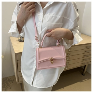 Dettaglio di una piccola borsa a tracolla rosa chiaro con fibbia dorata su una camicia bianca