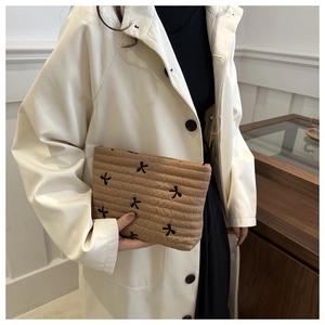 Detailaufnahme einer braunen gesteppten Kosmetiktasche mit schwarzen Schmetterlingsstickereien