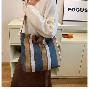 Vertical striped knit tote bag in blue, brown, and white with wide shoulder straps