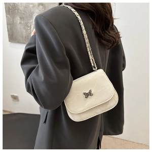 Detail of crossbody bag featuring marble texture, silver butterfly clasp and chain strap