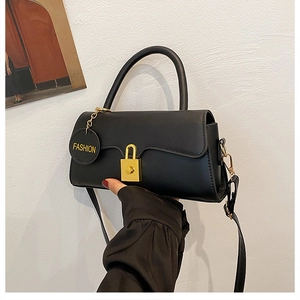 Detail of a black leather crossbody bag featuring a gold buckle and fashion charm