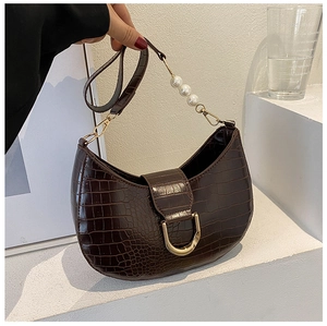 Detail of dark brown faux-crocodile texture bag with elegant pearl and metal chain handle