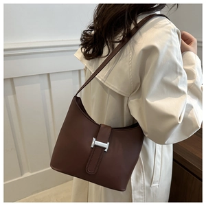 Close-up of brown leather shoulder bag featuring a silver H-shaped metal buckle detail